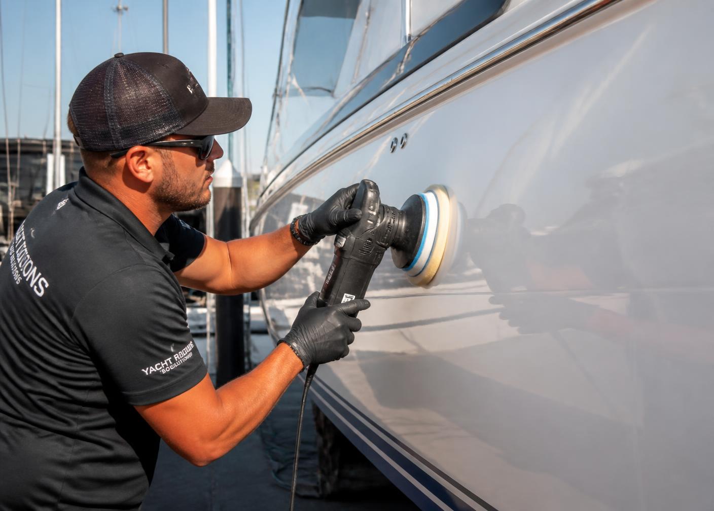 Marine detailer polishing a boat hull at a marina